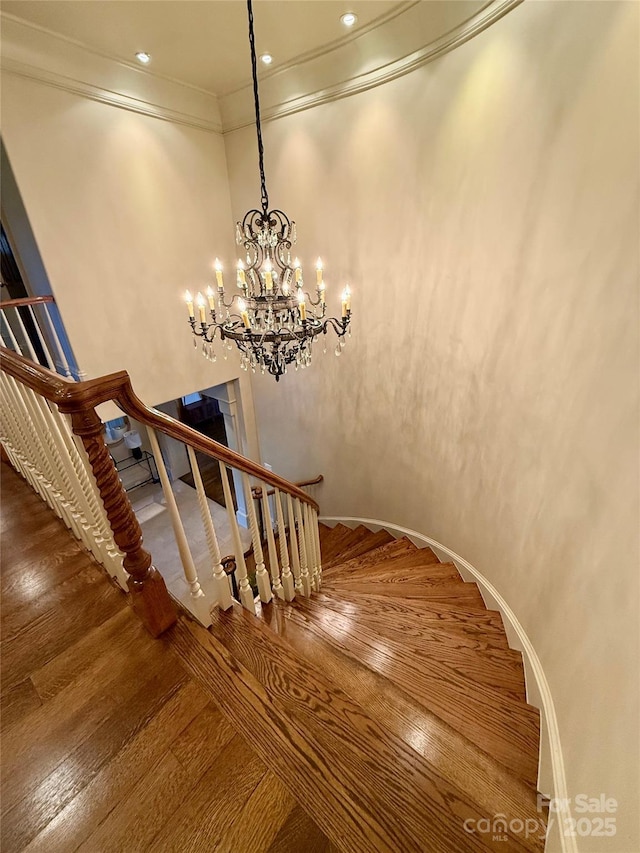 stairway with crown molding, arched walkways, and wood finished floors