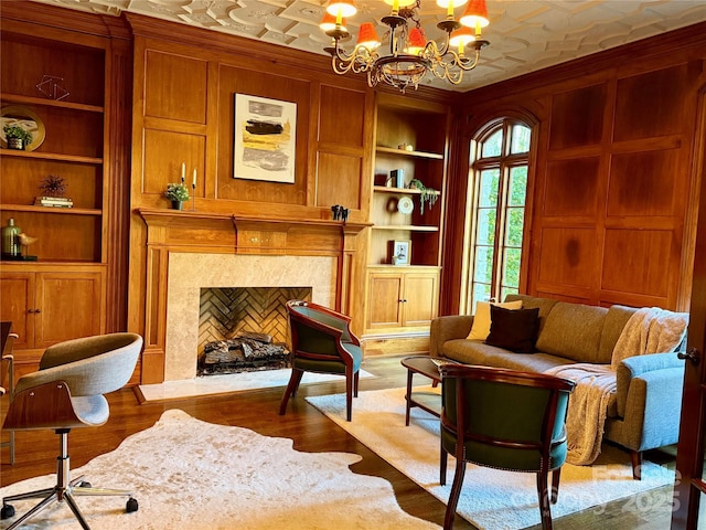 sitting room featuring built in features, light wood-type flooring, wood walls, and a premium fireplace