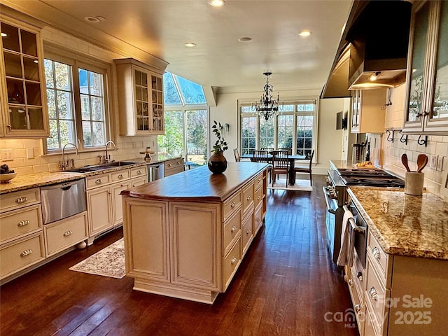 kitchen featuring premium range hood, a kitchen island, a warming drawer, glass insert cabinets, and pendant lighting