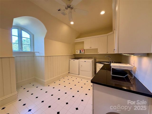 kitchen with dark countertops, wainscoting, white cabinetry, a sink, and separate washer and dryer