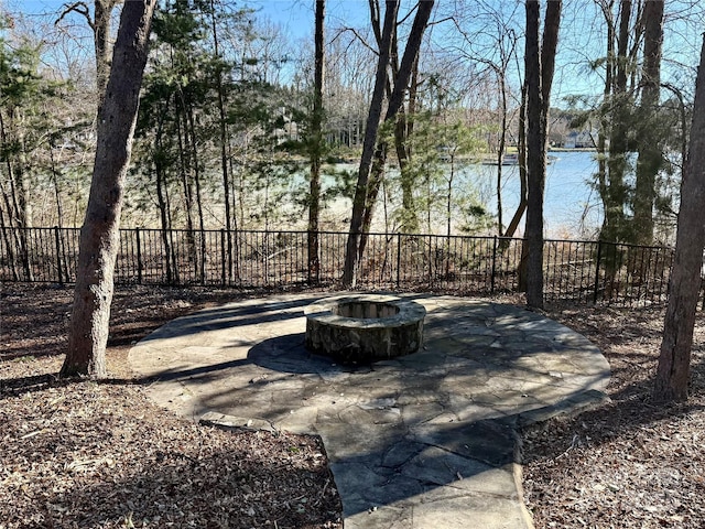 view of patio with a fire pit, a water view, and fence