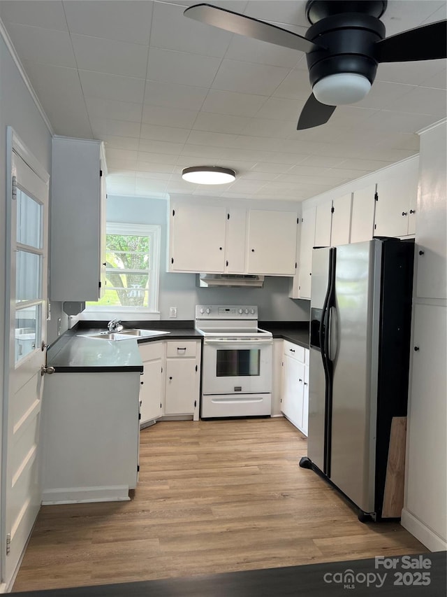 kitchen with electric stove, dark countertops, stainless steel fridge, and under cabinet range hood