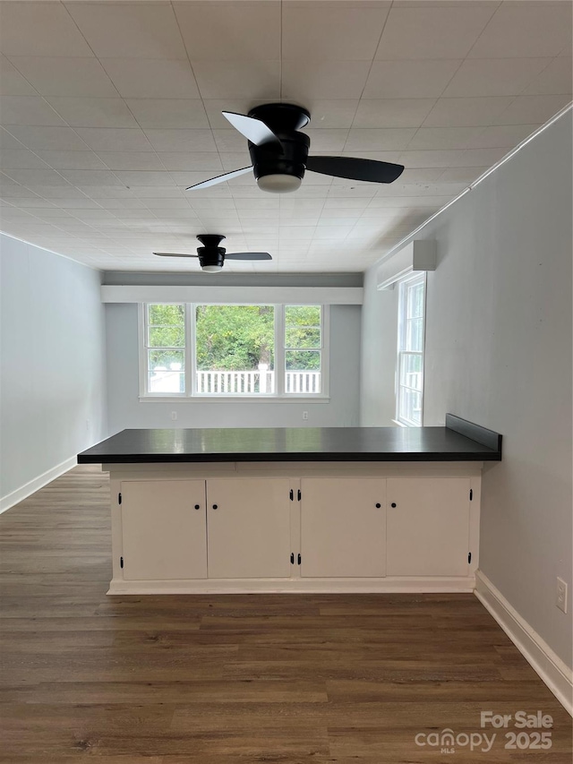 kitchen featuring dark countertops, ceiling fan, a peninsula, and white cabinetry