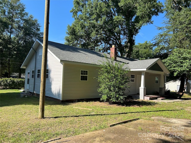 exterior space featuring a shingled roof, a lawn, and a chimney