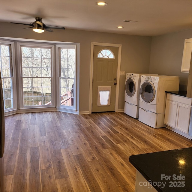 washroom featuring visible vents, washer and clothes dryer, wood finished floors, and cabinet space