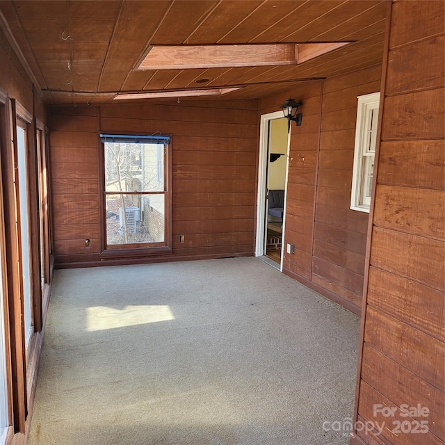 carpeted spare room featuring wood walls and wood ceiling