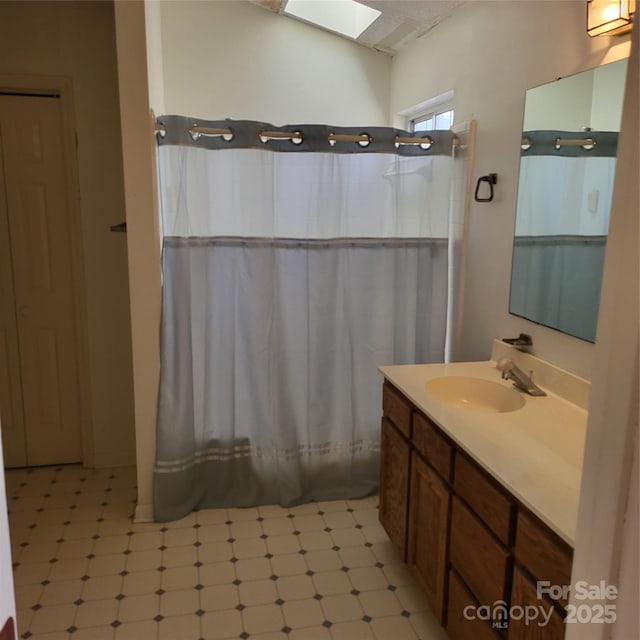 bathroom with curtained shower, a skylight, and vanity