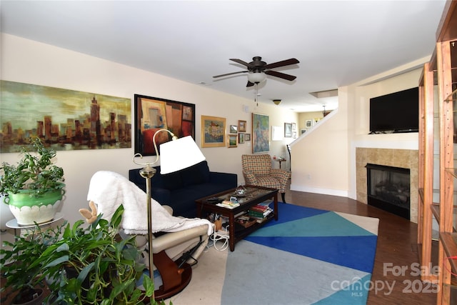 living room with a ceiling fan, baseboards, and a tiled fireplace