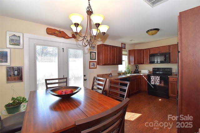 dining space with dark wood-type flooring, visible vents, and an inviting chandelier