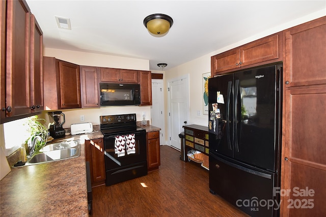 kitchen featuring black appliances, dark wood-type flooring, a sink, and visible vents