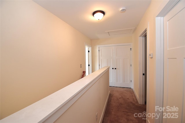 corridor with attic access, dark colored carpet, and an upstairs landing