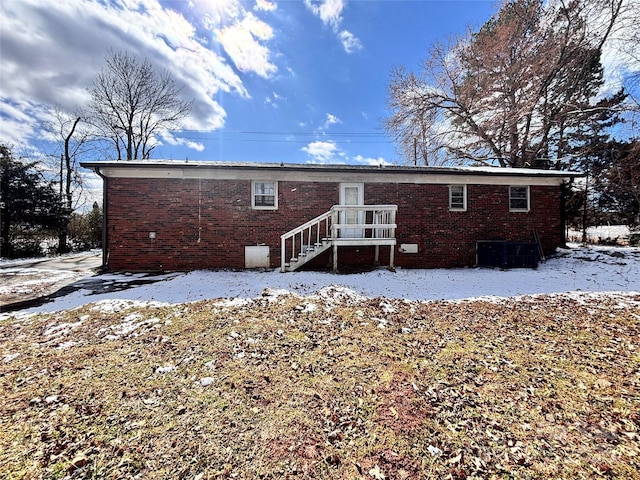 snow covered house featuring brick siding