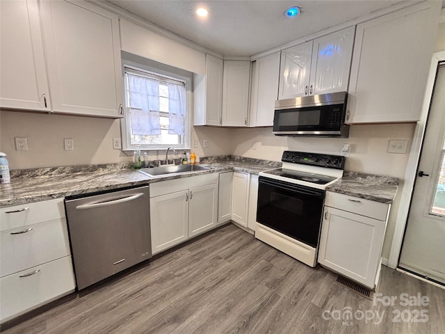 kitchen with appliances with stainless steel finishes, white cabinets, and a sink