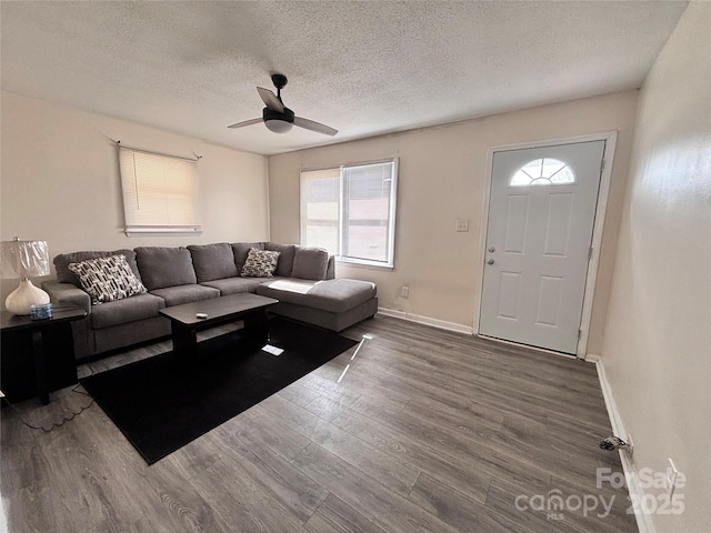 living area with ceiling fan, a textured ceiling, baseboards, and wood finished floors