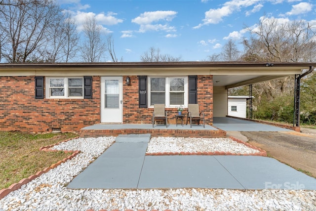 ranch-style house featuring crawl space, an attached carport, driveway, and brick siding