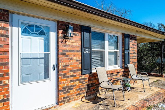 entrance to property with brick siding and a porch