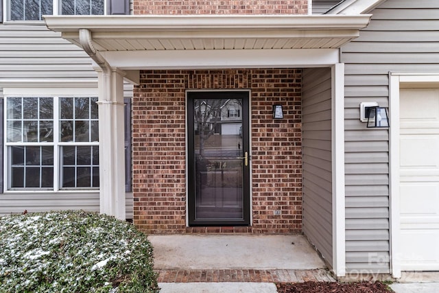 property entrance with brick siding and an attached garage