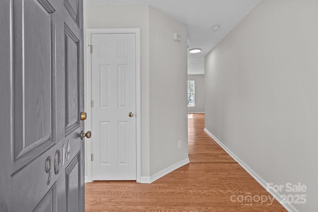 corridor featuring light wood-style flooring and baseboards