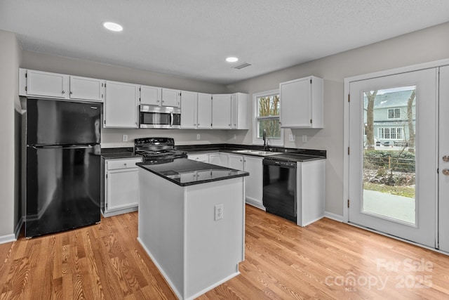 kitchen featuring a kitchen island, visible vents, white cabinetry, black appliances, and dark countertops