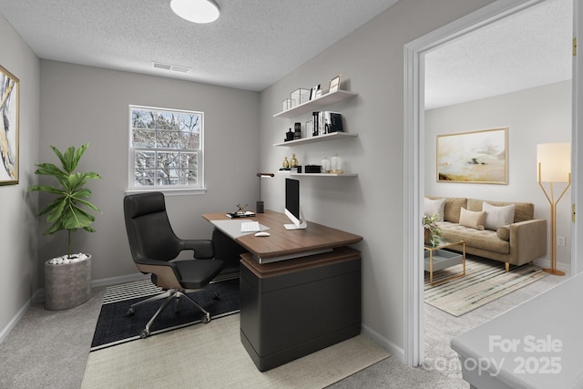 office with baseboards, carpet flooring, visible vents, and a textured ceiling