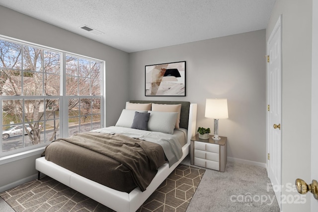 bedroom featuring baseboards, carpet, visible vents, and a textured ceiling