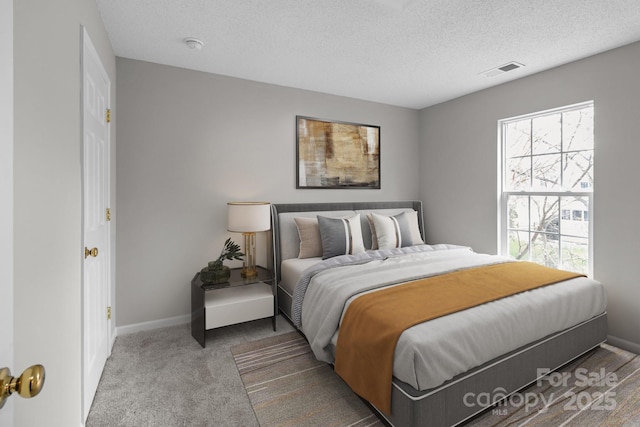 carpeted bedroom featuring baseboards, visible vents, and a textured ceiling