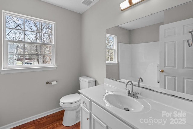 bathroom with visible vents, toilet, vanity, wood finished floors, and baseboards