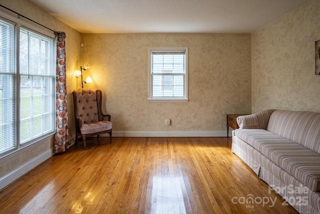 sitting room with baseboards, a wealth of natural light, and light wood-style floors