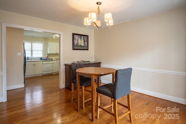 dining room with a chandelier, light wood-type flooring, and baseboards