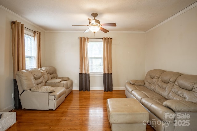 living area with ornamental molding, ceiling fan, baseboards, and wood finished floors