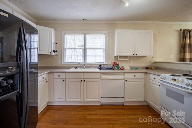 kitchen featuring light countertops, white appliances, a sink, and white cabinetry