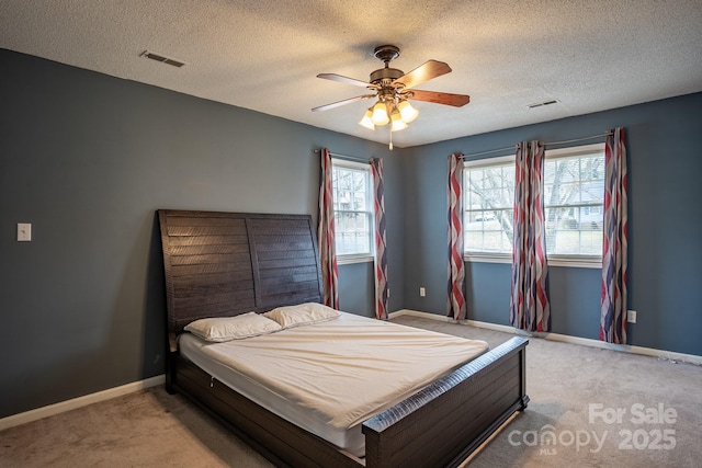 bedroom featuring light carpet, baseboards, visible vents, and a textured ceiling