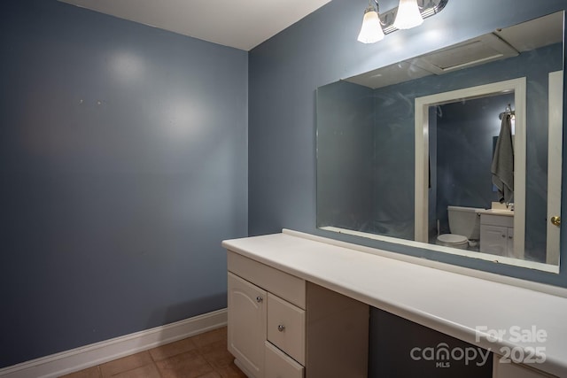 bathroom with tile patterned flooring, baseboards, vanity, and toilet