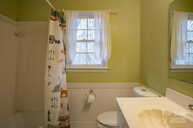 bathroom featuring a wainscoted wall, toilet, vanity, and shower / tub combo with curtain