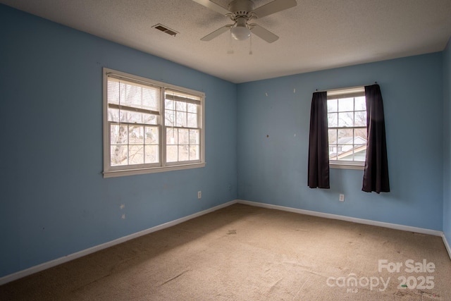 unfurnished room with a textured ceiling, carpet, visible vents, and baseboards