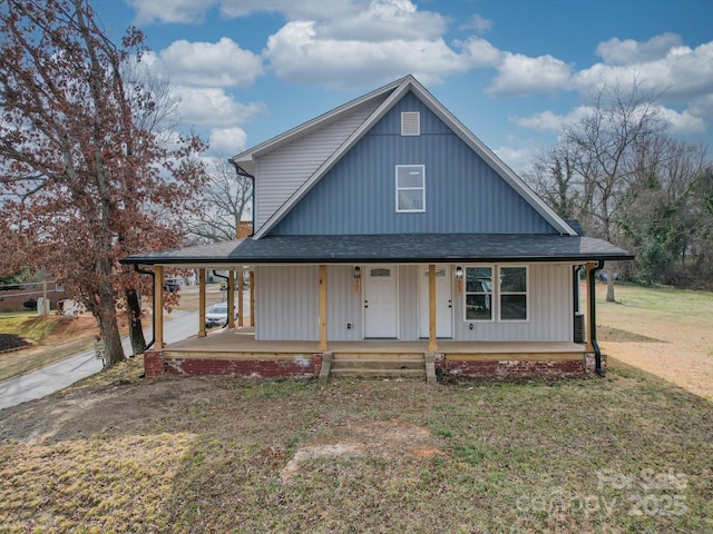 farmhouse inspired home with a porch, a front yard, an attached carport, and a shingled roof