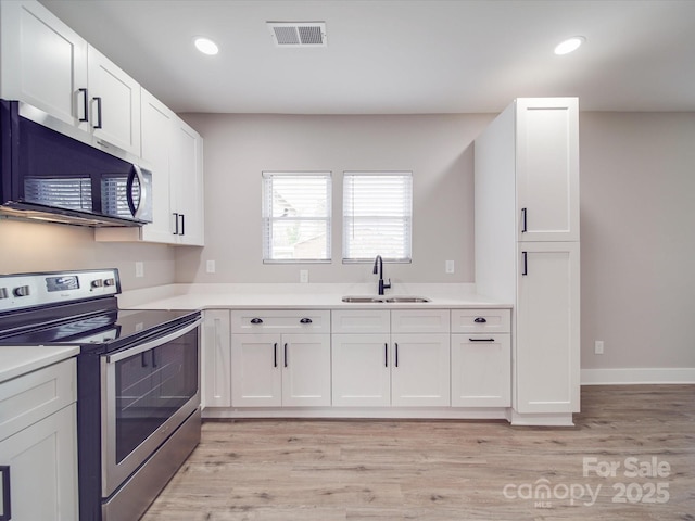 kitchen with visible vents, white cabinets, stainless steel appliances, light countertops, and a sink