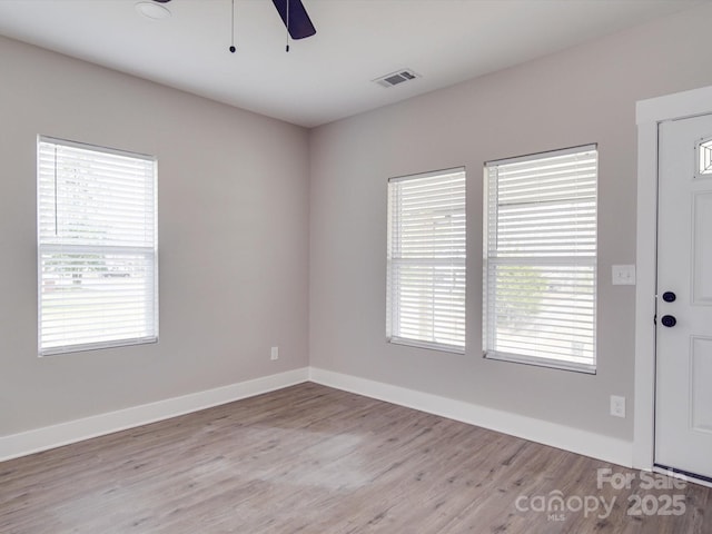 unfurnished room featuring a ceiling fan, baseboards, visible vents, and wood finished floors