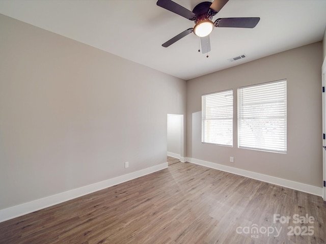 spare room with visible vents, ceiling fan, baseboards, and wood finished floors