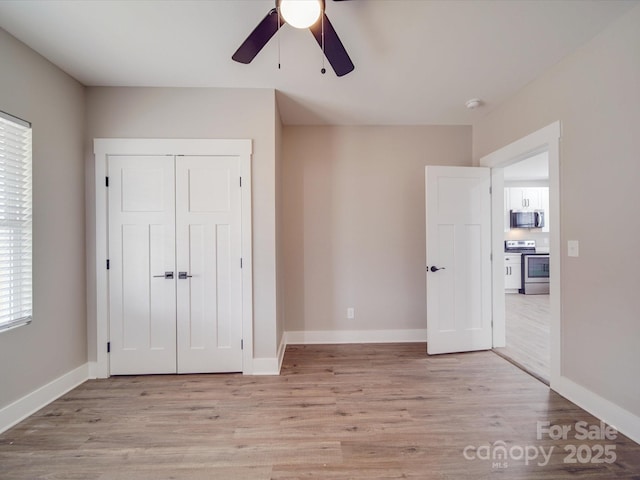 unfurnished bedroom with a closet, light wood-style flooring, and baseboards