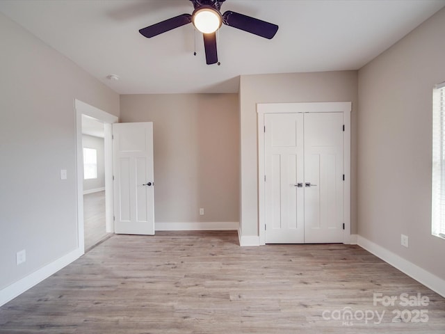 unfurnished bedroom with light wood-style flooring, baseboards, ceiling fan, and a closet