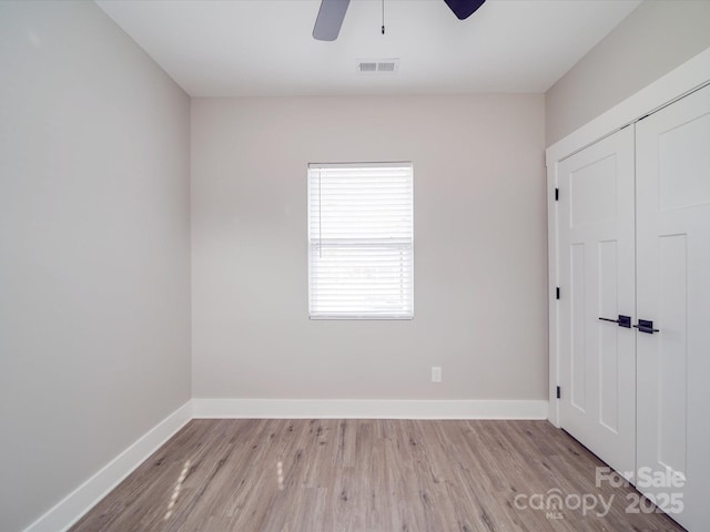 unfurnished bedroom with baseboards, a closet, visible vents, and wood finished floors