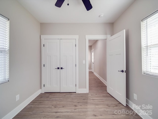 unfurnished bedroom featuring light wood-style floors, baseboards, and a closet