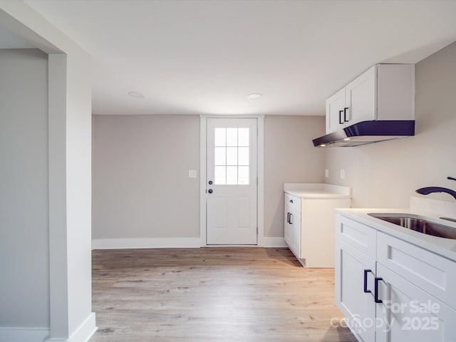 interior space featuring a sink, light wood-style flooring, and baseboards