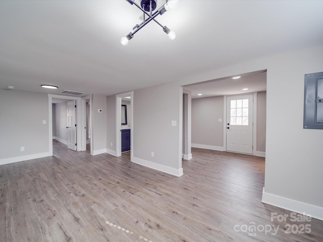 interior space featuring light wood-style floors, electric panel, visible vents, and baseboards