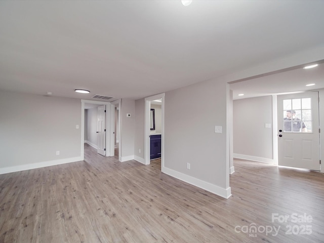 unfurnished living room with light wood-style floors, visible vents, and baseboards