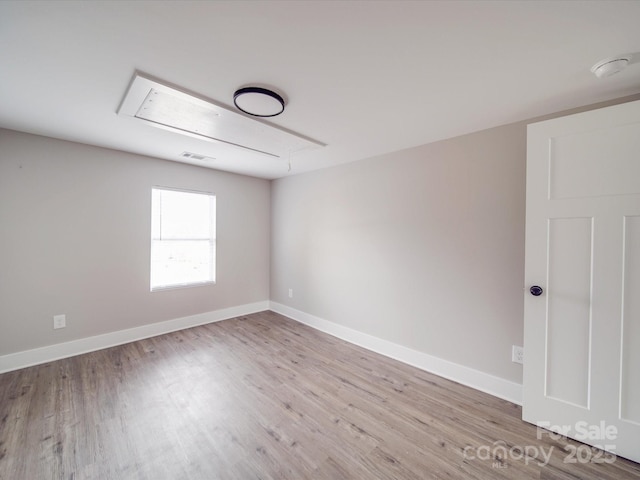 unfurnished room featuring attic access, visible vents, baseboards, and wood finished floors