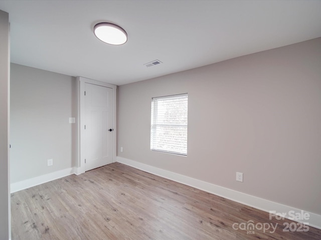 unfurnished room with visible vents, baseboards, and wood finished floors