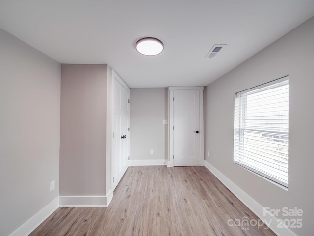 unfurnished room featuring visible vents, baseboards, and wood finished floors