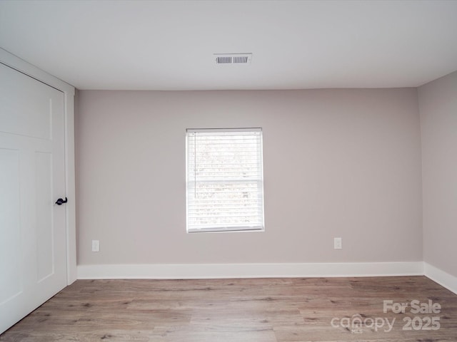 empty room with light wood-type flooring, baseboards, and visible vents